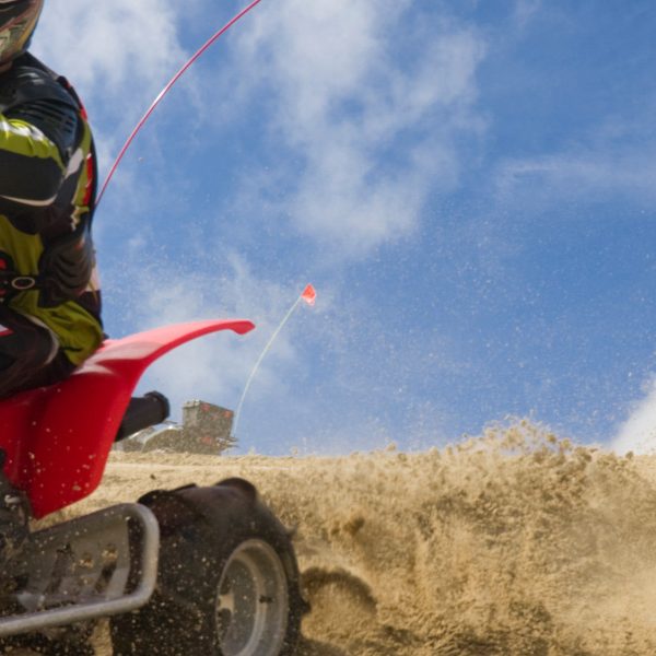 A person riding an ATV through a sand pit at perilously high speed.